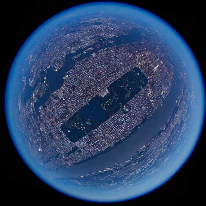 Fisheye view of New York City from above, with Central Park prominently in the center, surrounded by dense buildings, rivers, and a blue atmospheric edge encircling the curvature of the Earth.