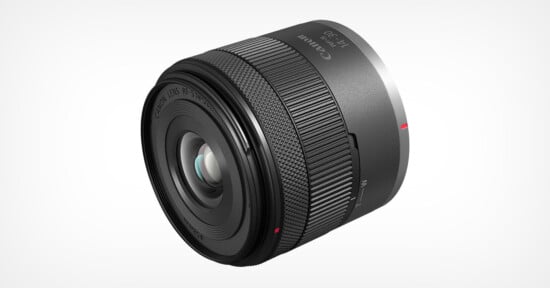 A Canon camera lens with a metallic finish. It features a textured focus ring and visible text indicating "Canon" and "RF 30." The lens is slightly tilted, showcasing its glass elements and markings. The background is plain white.