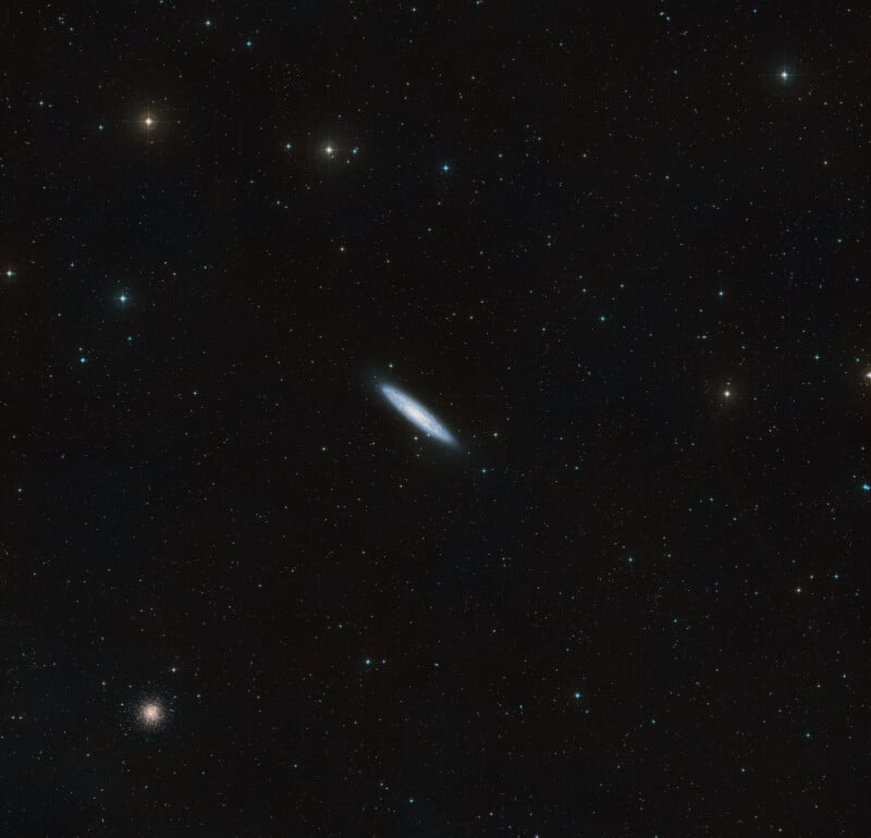 A dark sky filled with countless stars features a bright, elongated galaxy at the center. In the lower left, a dense, round cluster of stars stands out against the scattered stars around it.