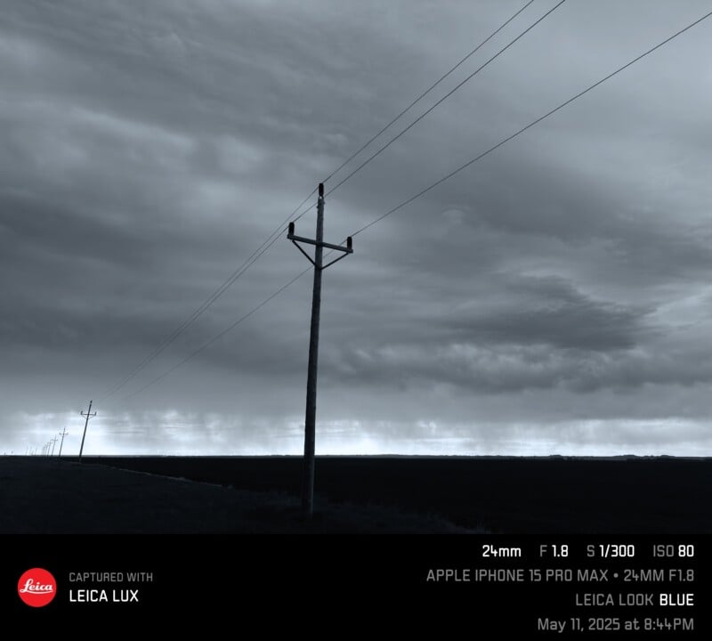A moody, overcast sky stretches above a flat landscape with power lines receding into the distance. The scene is tinted blue, creating a dramatic and somber atmosphere.