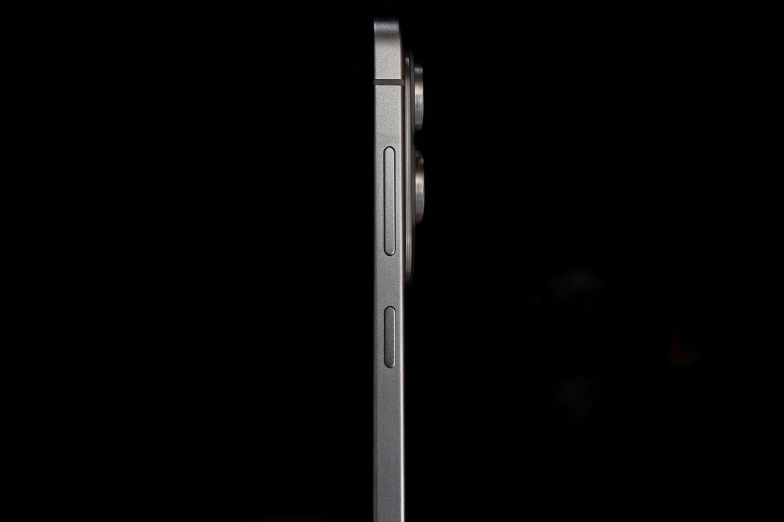 A close-up side view of a modern smartphone, showing the volume buttons and camera bump against a black background.