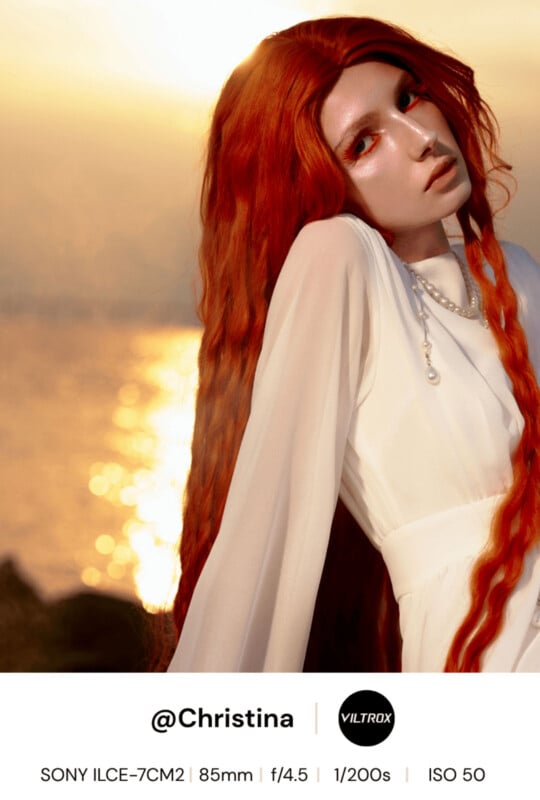 A woman with long, wavy red hair poses in a white dress by the sea at sunset. The golden sunlight highlights her features. Text at the bottom credits @Christina and lists camera settings and equipment details.